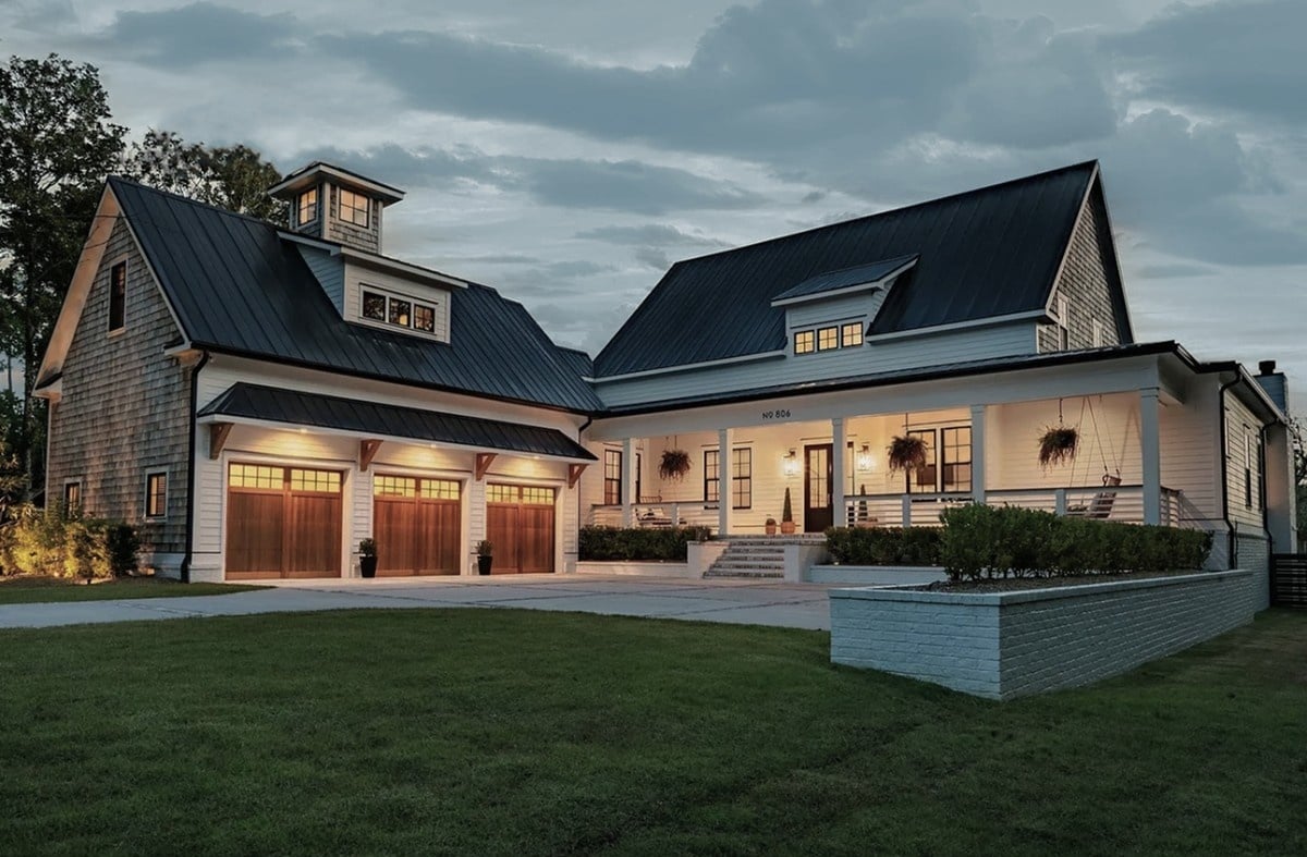 White house built by Coastal Cypress, three garages, dimly lit at dusk
